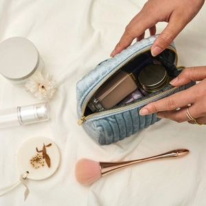Detailed top view of light blue quilted velvet makeup bag being used for storage