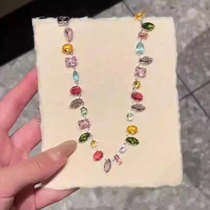 Colorful multi-shape crystal gemstone necklace with silver chain on a hand-held display