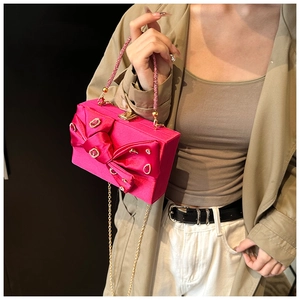 Close-up of rose red evening bag featuring a silk bow and sparkling rhinestones