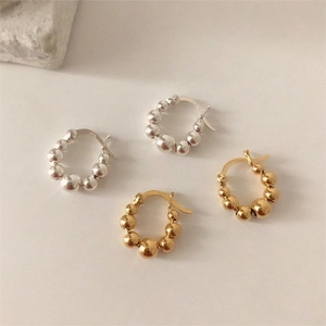 Close-up of S925 sterling silver beaded hoop earrings in gold and silver finishes
