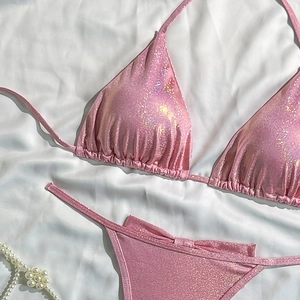 Close-up of pink metallic sequin bikini set with drawstring details on white silk