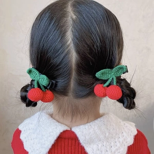Detail of handmade crochet cherry hair clips with green leaves worn on braided hair
