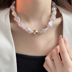 Gros plan sur un collier de perles baroques élégant avec un pendentif en métal doré chic