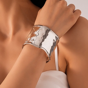 Detailed view of wide silver metallic cuff bracelet with irregular wrinkled texture surface