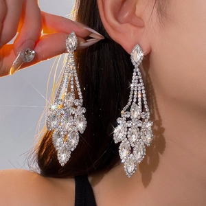 Gros plan de boucles d'oreilles à pompons argentés avec fleurs de diamant et cristaux