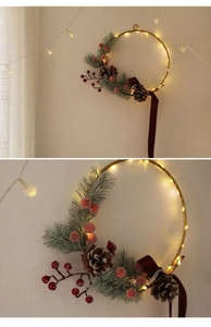 Detail of a lighted Christmas wreath with pine needles, red berries, and pinecones