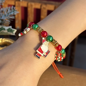 Close-up of Santa and gift box charms on a festive hand-woven adjustable beaded bracelet