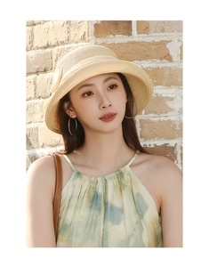 Détail d'un chapeau de soleil en paille beige avec ruban à nœud et design à larges bords
