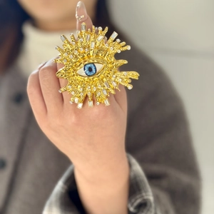 Detalle de pulsera ancha dorada vintage con diseño de ojo turco y diamantes brillantes