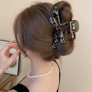 Detail of leopard print acetate bow hair claw clip styled on woman's updo hairstyle