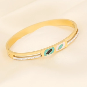Detail of gold evil eye bangle with blue enamel, crystals, and silk background