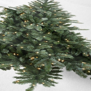Detail of Christmas tree tapestry showing green pine branches with warm glowing lights