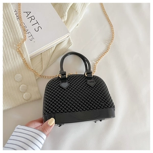 Detail of black mini jelly bag with beaded texture and gold chain shoulder strap