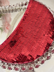 Detailed macro view of vibrant red sequins and large crystal diamonds on a party handbag