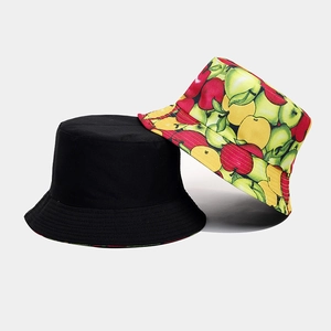 Detailed view of reversible bucket hat showing black side and colorful fruit pattern fabric