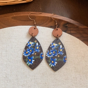 Detail shot of bohemian wooden teardrop earrings with blue floral prints on cotton background