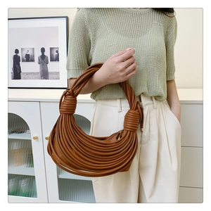 Detail view of caramel pleated knot underarm bag with unique layered leather cord texture