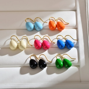 Detailed view of teardrop earrings in seven bright candy colors on a white jewelry display