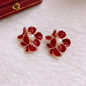 Detail von roten Blumen und Schmetterlingsohrringen mit Goldkanten und Perlenakzenten