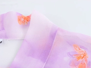 Detail of purple gradient chiffon fabric with orange floral print and ruffled stitching