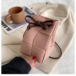 Detail of pink hand-woven leather bucket bag with brown drawstring and knot accents