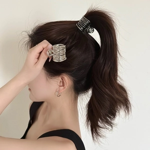 Detail of silver spiral claw clip holding a high ponytail securely on a model
