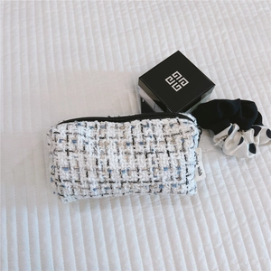 Detail of tweed makeup bag in milk white and blue plaid with black smooth zipper
