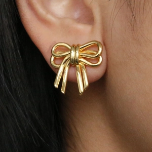 Elegant 18k gold ribbon bow earrings for women shown worn on a model's ear