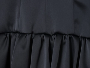 Gros plan d'une mini-robe en satin noir montrant les détails des plis et la texture du tissu