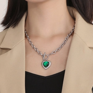 Detailed view of a green heart pendant necklace with OT toggle clasp worn by a model