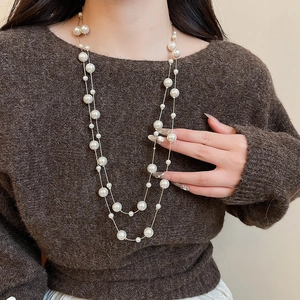 Close-up of layered pearl necklace with crystal beads and gold chain on sweater