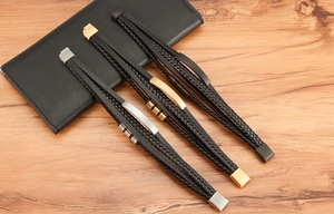 Close-up of triple layered black leather bracelets with gold, silver and black metal clasps