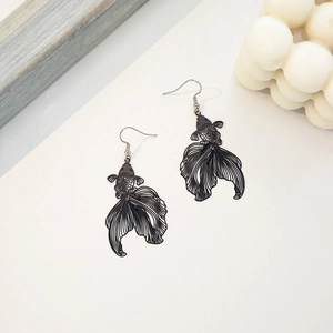 Macro shot of black goldfish earrings with intricate hollow patterns and metal hooks