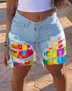 Detail of distressed denim shorts with colorful patchwork under raw-edge ripped holes