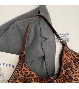 Close-up of leopard print shoulder bag with brown leather strap and soft fabric texture