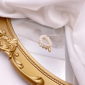 Detail of double-layer freshwater pearl ring with a golden U-shaped charm and silk accents