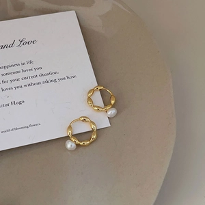 French vintage style gold twisted hoop earrings with white pearls on a minimalist background