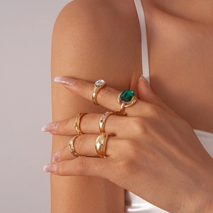 Close-up of model wearing gold vintage rings set with emerald and zircon gemstones