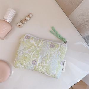 Close-up of floral cotton pouch with green cord zipper and delicate floral pattern
