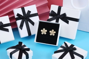 Detail of elegant champagne floral earrings inside a premium white textured jewelry box