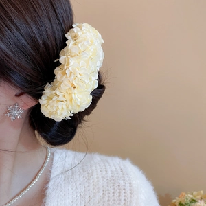 Detailed side view of a cream fabric floral hair pin styled in an elegant updo hairstyle