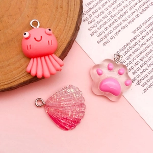 Detail of pink resin DIY charms featuring a cat paw, octopus and glittery shell with rings