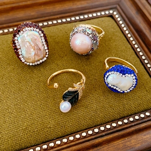 Detailed close-up of vintage gold-plated rings with pearls and diamonds on velvet stand