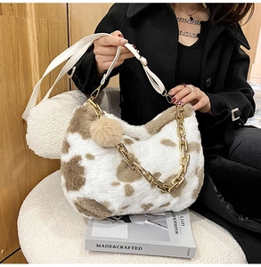 Detail of faux fur tote bag with cow print pattern and thick gold chain strap