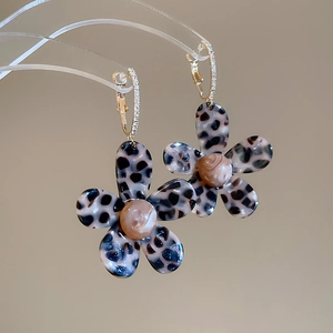 Detailed close-up of tortoise shell acetate flower earrings with gold zircon hoops