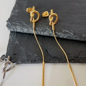 Detail of knot earrings with long snake chain tassels in gold and silver finish