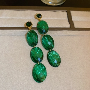 Detailed view of vintage emerald green faceted oval drop earrings with golden metal base
