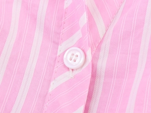 Macro detail of pink striped shirt dress with a white button and neat stitching
