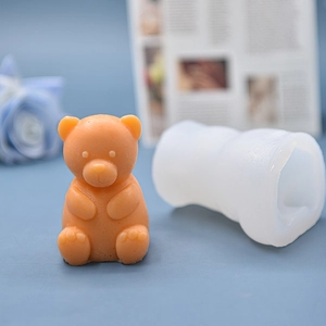 Cute sitting bear silicone mold with orange finished candle on a blue background