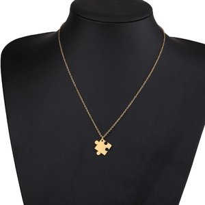 Détail du collier à pendentif puzzle doré sur mannequin noir montrant des bijoux de couple